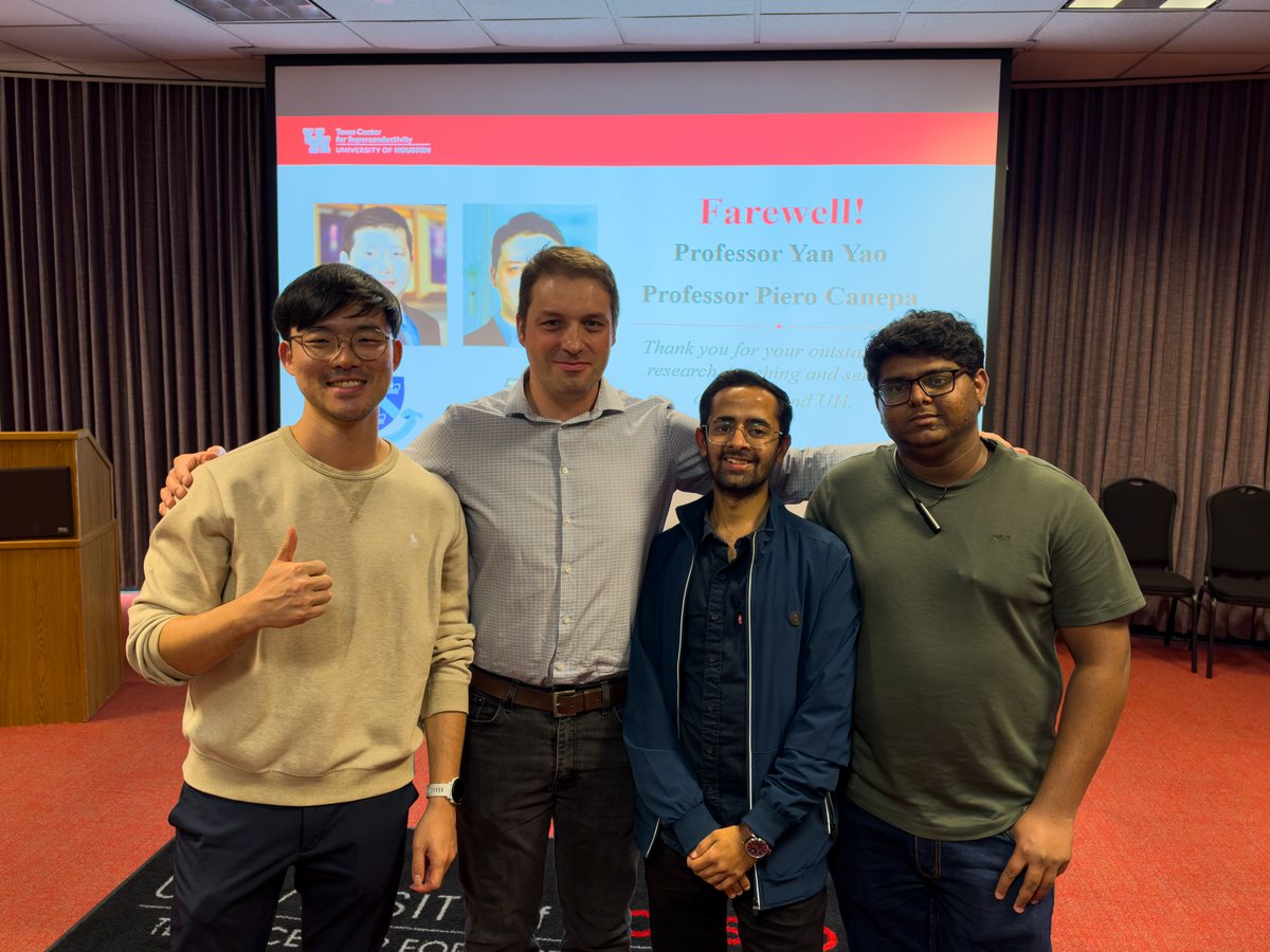 Four members of the group standing arm in arm in front of a screen reading "Farewell!", one giving a thumbs-up